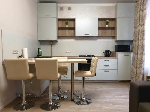 a kitchen with white cabinets and a table and chairs at Apartment Sweethome 2 FREE PARKING in Uzhhorod