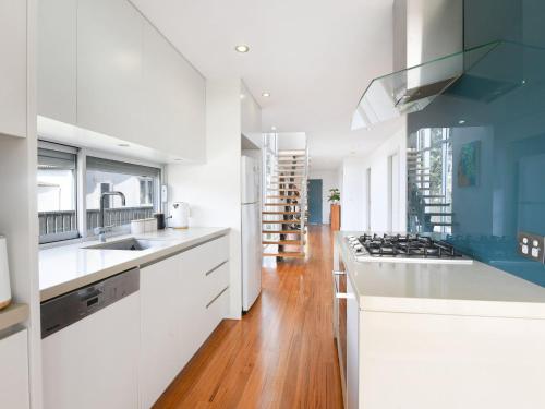 a kitchen with white cabinets and blue accents at Rangoon Sunrise at Minnamurra in Minnamurra