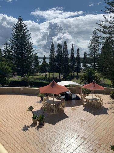 a patio with tables and umbrellas on a patio at Northpoint Apartments in Port Macquarie