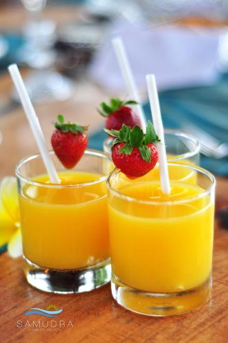 two glasses of orange juice and strawberries on a table at Villa Samudra Luxury Beachfront in Ketewel