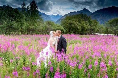 a bride and groom kissing in a field of flowers at Majestic Valley Wilderness Lodge in Sutton