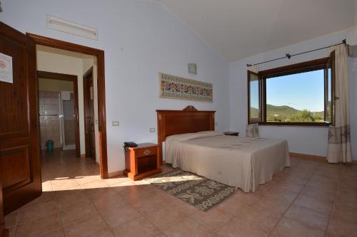 a bedroom with a bed and a large window at Albergo Ristorante Pizzeria Monte Arcosu in Uta