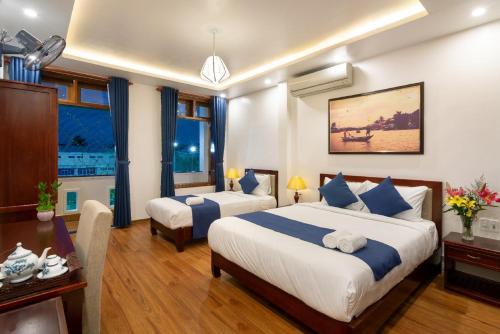 ホイアンにあるThe Linh Hoi An Villaのベッド2台とデスクが備わるホテルルームです。