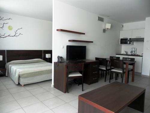 sypialnia z biurkiem i łóżkiem oraz kuchnia w obiekcie Residence Services Calypso Calanques Plage w Marsylii