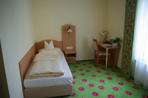 a small bedroom with a bed and a desk at Hotel Gaum in Biberach-Ummendorf