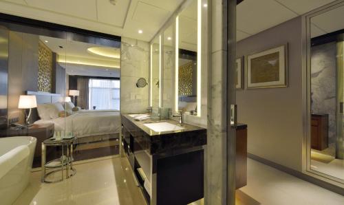 a bathroom with a sink and a bed and a tub at Kempinski Hotel Taiyuan in Taiyuan