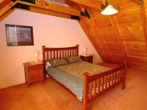 a bedroom with a wooden bed and two night stands at Rosewood Cottage in Dunsborough
