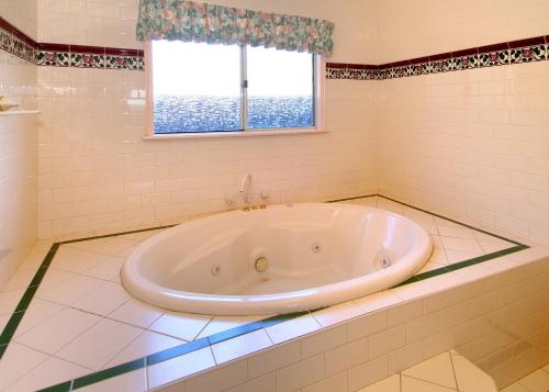 a large tub in a bathroom with a window at Rosewood Cottage in Dunsborough