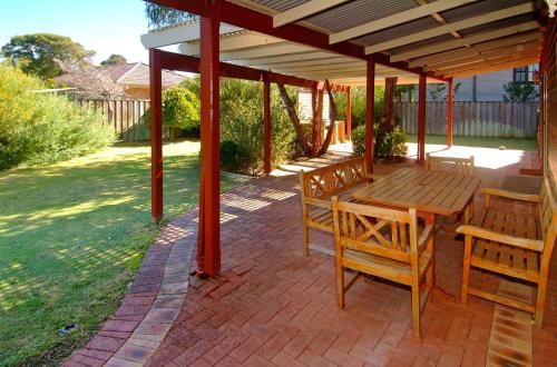 a patio with a wooden table and chairs under a pavilion at Rosewood Cottage in Dunsborough