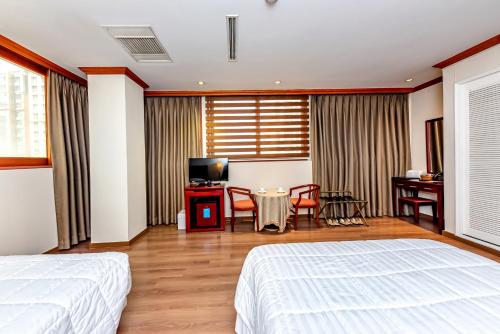 a bedroom with a bed and a table with chairs at Samhaein Hotel in Jeju