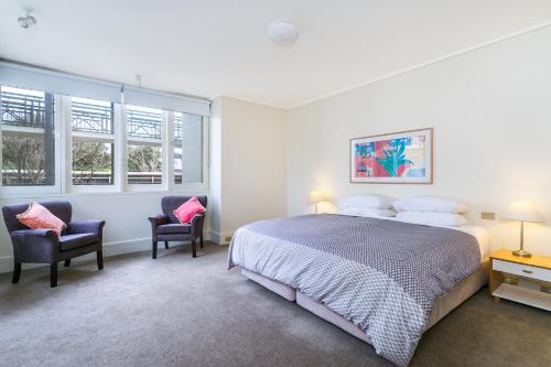 une chambre avec un grand lit et deux chaises dans l'établissement Portsea Village Resort, à Portsea