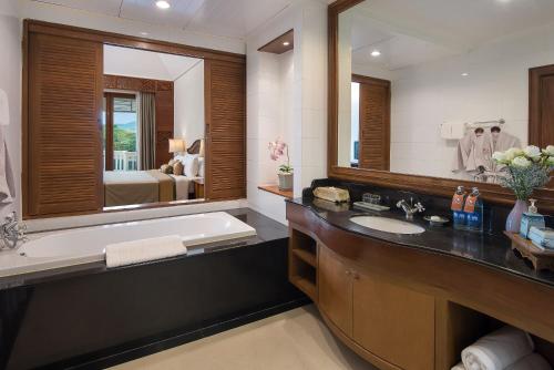 a bathroom with a tub and a large mirror at Dheva Mantra Resort in Kanchanaburi City