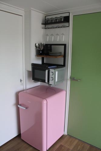 a pink refrigerator in a room next to a door at Bed & Breakfast Aalsmeer in Aalsmeer
