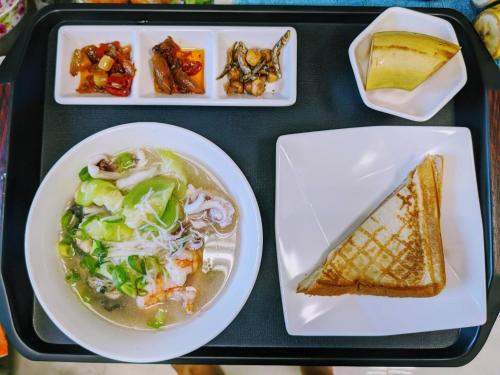 a tray of food with a plate of soup and a sandwich at Shell Sand Homestay in Magong