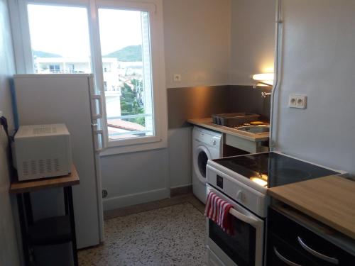 a kitchen with a stove and a refrigerator and a window at Charmant F2 avec vue, proche centre in Clermont-Ferrand