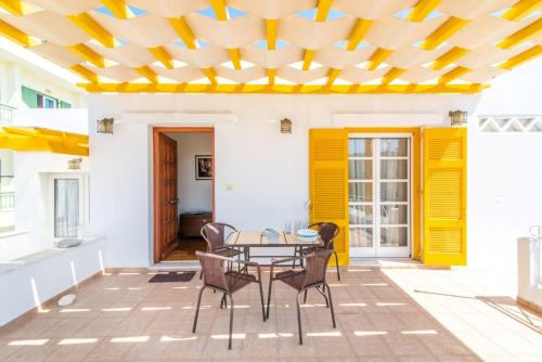 un patio con tavolo, sedie e soffitto giallo di Estia Tinos a Città di Tinos