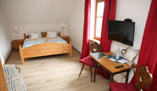 Schlafzimmer mit einem Bett, einem Tisch und einem TV in der Unterkunft Gasthof Schloßbräu Lintach in Freudenberg