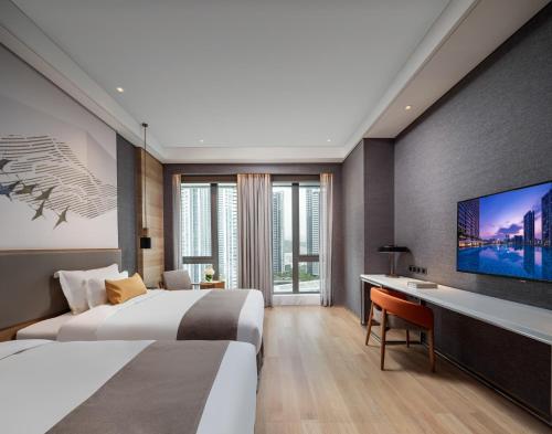 a hotel room with two beds and a flat screen tv at Genpla Hotel Shenzhen Nanshan in Shenzhen