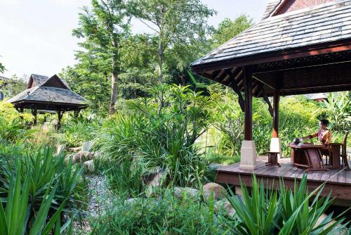 a person sitting at a table on a deck in a garden at InterContinental Xishuangbanna Resort by IHG in Jinghong