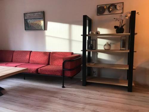 a living room with a red couch and shelves at De Specht in Bergen