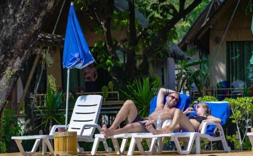 two people laying in lawn chairs on the beach at Anyavee Krabi Beach Resort in Klong Muang Beach