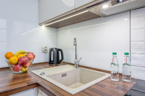 a kitchen with a sink and a bowl of fruit at Apartamenty K2 Podmurna 36 in Toruń