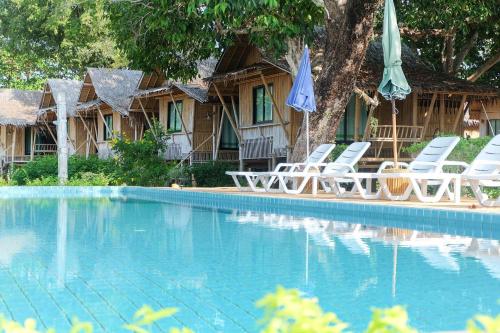 una casa con sillas y sombrillas junto a una piscina en Anyavee Krabi Beach Resort formerly known as Bann Chom Le Beach Resort, en Klong Muang Beach