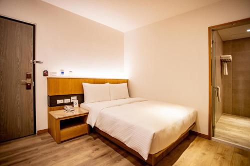 a bedroom with a white bed and a wooden table at Beauty Avenue Inn in Kaohsiung