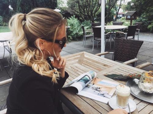 a woman sitting at a table with a cup of coffee at Hotel Landhaus Krombach in Elkenroth