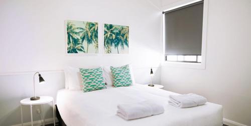 a bedroom with a white bed with two pillows at Hibiscus Motel in Byron Bay