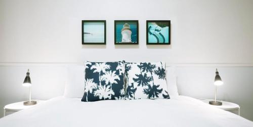 a bedroom with a white bed with three pictures above it at Hibiscus Motel in Byron Bay