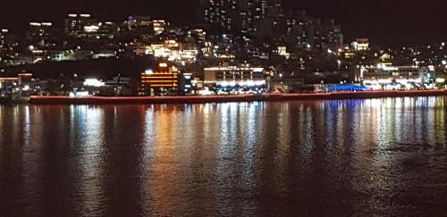 a view of a city at night from the water at Lium Spa Hostel in Yeosu
