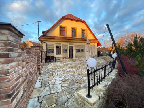 a small yellow house with a brick wall at Penzion LaCasa in Vysoké Mýto