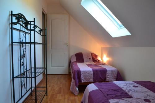 une chambre mansardée avec deux lits et une lucarne dans l'établissement Gîte Les Vents du Large L'Aigrette, au Crotoy