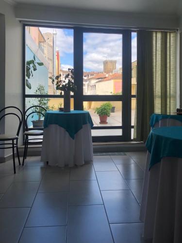 a room with two tables and a large window at Hotel Termas in Chaves