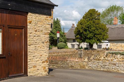 a stone building with a wooden door and a yard at Church Farm Lodge in Harrington