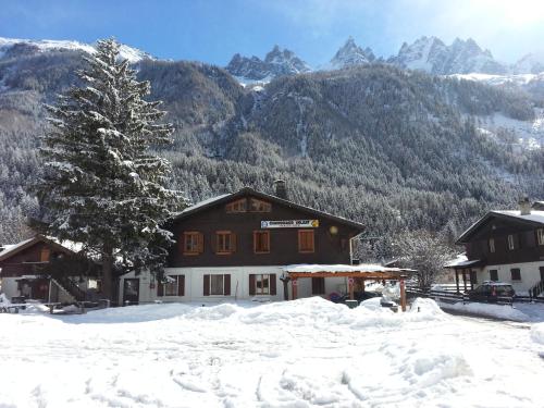 una casa en la nieve con montañas en el fondo en Le Chamoniard Volant en Chamonix-Mont-Blanc