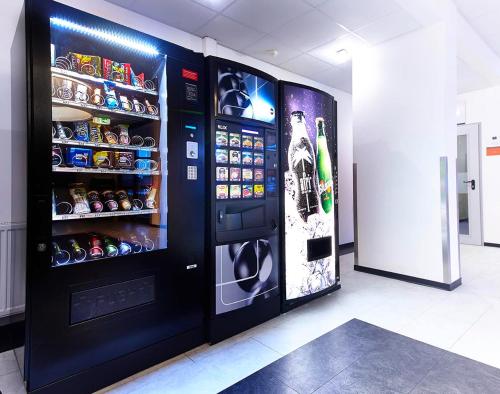 a black vending machine in a room with drinks at Road House Hotel in Paderborn
