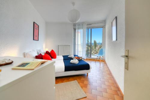 - une chambre avec un lit doté d'oreillers bleus et rouges dans l'établissement Bord de plage - Première conciergerie, à Palavas-les-Flots