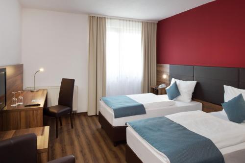 a hotel room with two beds and a desk at ACHAT Hotel Wetzlar in Wetzlar