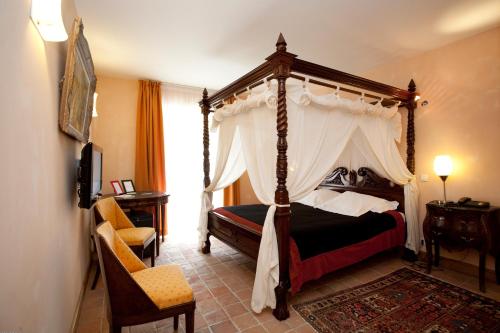 サント・モール・ド・トゥレーヌにあるHostellerie Les Hauts De Sainte Maureのベッドルーム(天蓋付きベッド1台、椅子付)