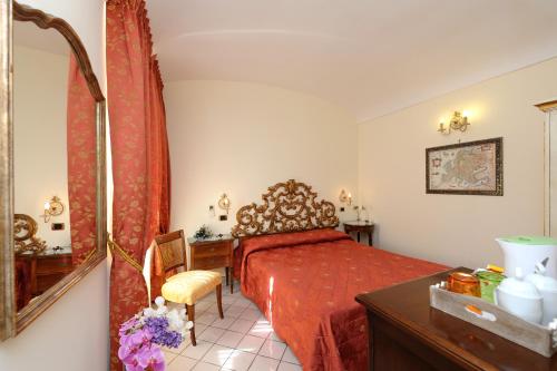 a bedroom with a bed and a desk and a mirror at Amalfi Old Square room & apartments , 73 steps from the street in Amalfi