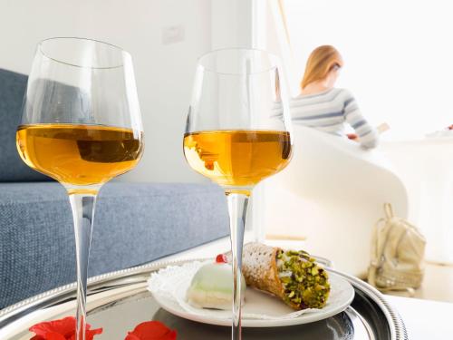 two glasses of wine and a plate of food on a tray at White Bay in Fontane Bianche