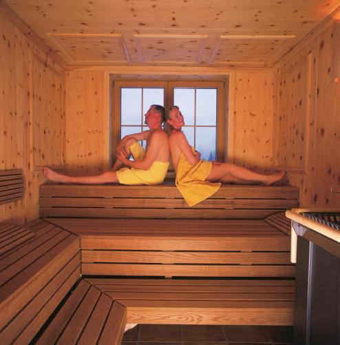 a group of three people sitting in a sauna at Hotel Huber Hochland in Maurach