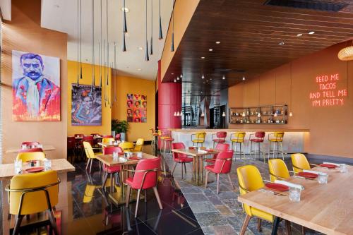 a restaurant with yellow and red chairs and tables at Park Inn by Radisson Abu Dhabi Yas Island in Abu Dhabi