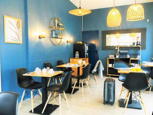 ein Restaurant mit blauen Wänden, Tischen und Stühlen in der Unterkunft Hôtel Jules in Le Touquet-Paris-Plage