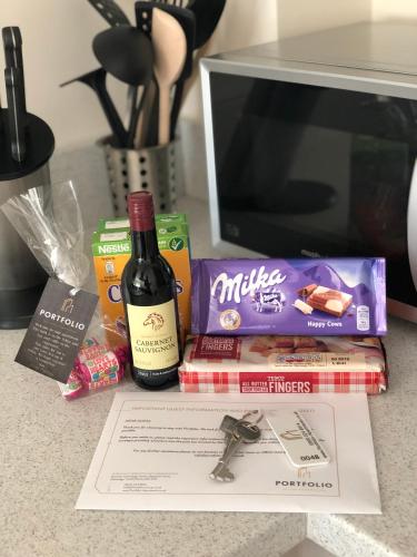 a table with a bottle of wine and a pile of food at Portfolio Apartments - Welwyn Business Park in Welwyn Garden City