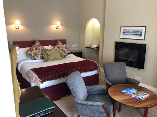 a hotel room with a bed and a table and chairs at Coul House Hotel in Contin