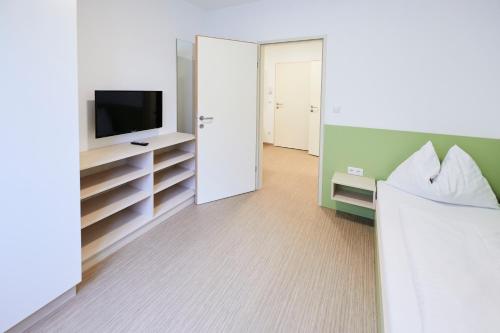 a bedroom with a bed and a tv and a room at I AM HOTEL Leoben in Leoben