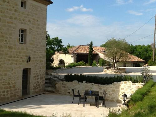 un patio avec une table et des chaises devant un bâtiment dans l'établissement Gites Loste, à Beauville